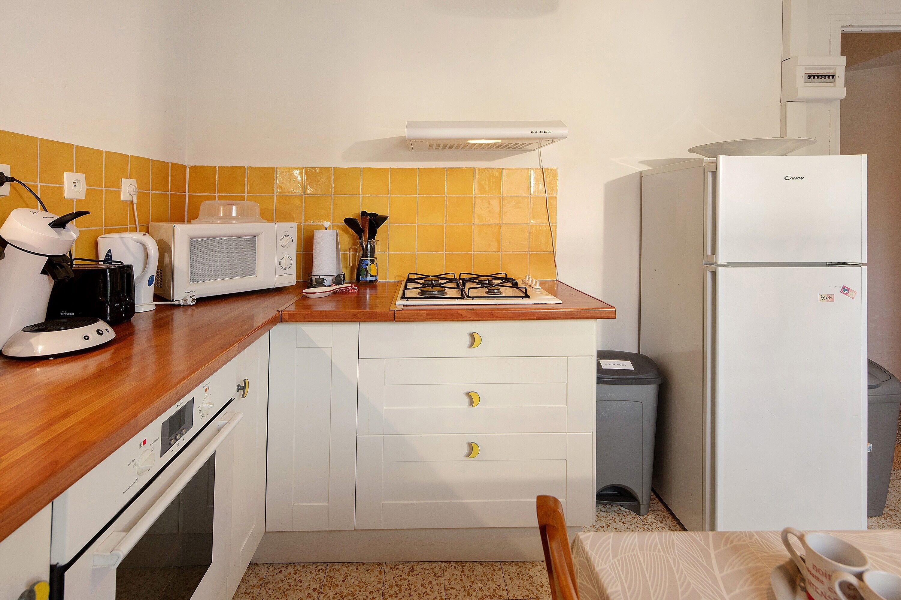 Een keuken met een magnetron, broodrooster, gasfornuis en een koelkast.