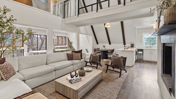 A spacious living area with a high ceiling, a dining area, and a kitchen.