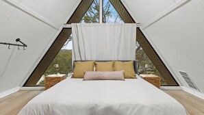 A bedroom with a bed, pillows, and a view through a triangular window.