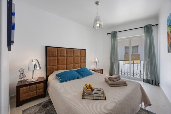 A bedroom with a bed, nightstands, a tray with food and drinks, and a balcony with curtains. - Family Apartment in the Historic Center (Lagos)