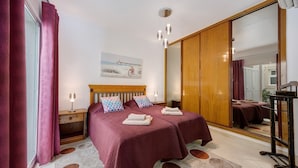 A bedroom with a bed, bedside tables, a mirror, and a painting on the wall.