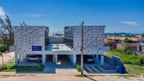 A modern building with a geometric facade, a covered parking area, and a sign indicating 'Peak Loft Studio'. - Lofts completos e modernos em Jaguaruna a 50m da Praia - PLO (Jaguaruna)
