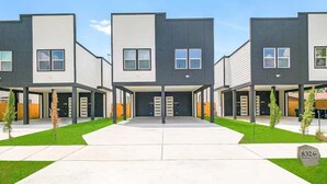 Un immeuble d’appartements moderne doté d’une cour intérieure, de plusieurs entrées et d’une pelouse bien entretenue.