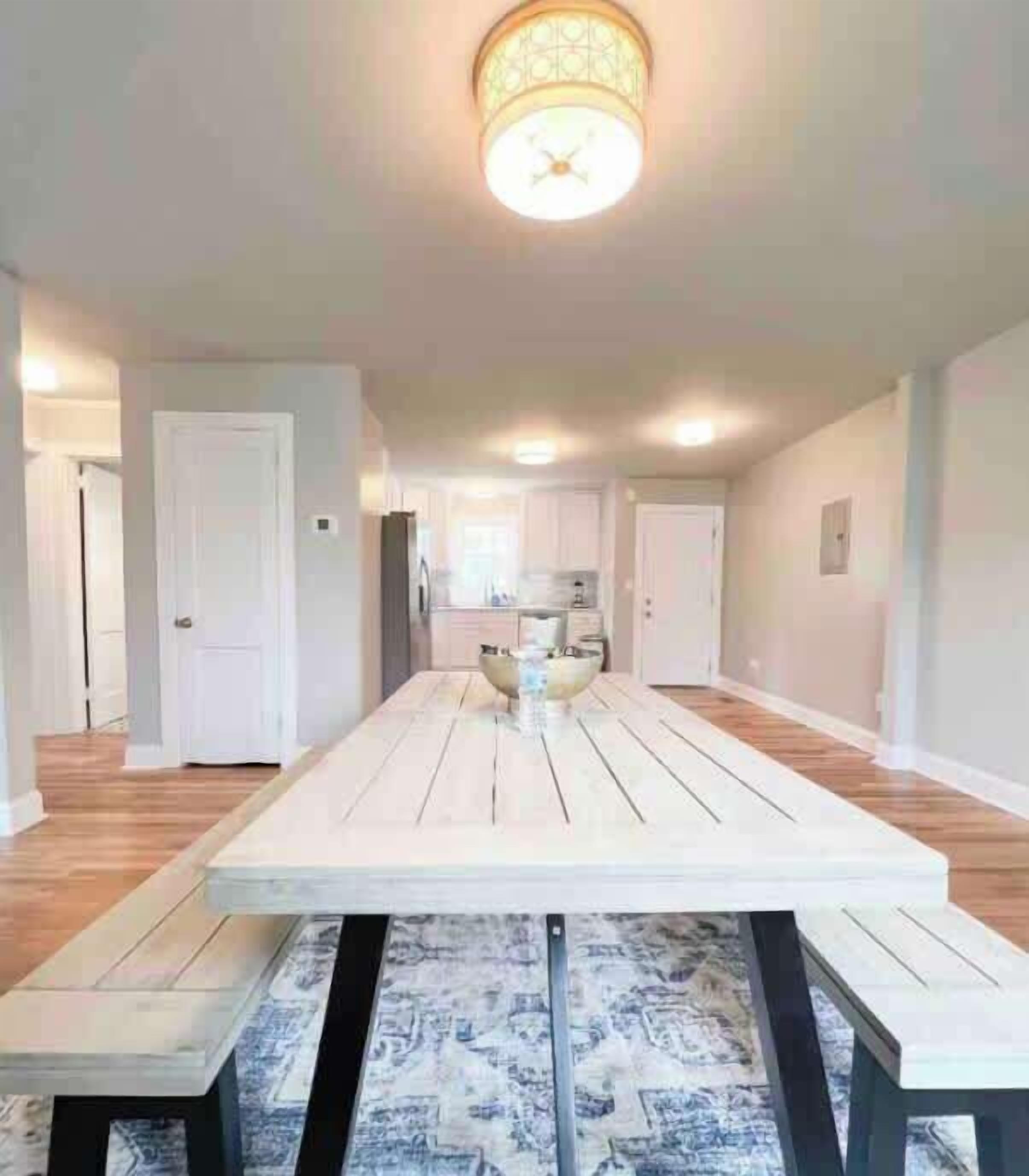 A spacious dining area with a long table, benches, and a patterned rug.