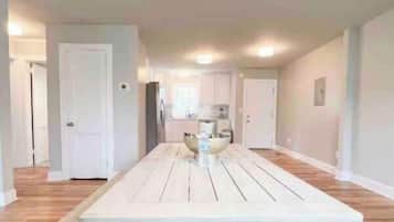 A spacious dining area with a long table, benches, and a patterned rug.