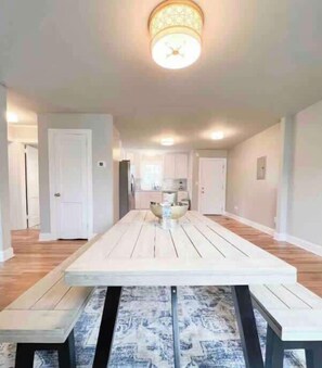 A spacious dining area with a long table, benches, and a patterned rug.
