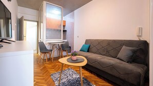 Un salon moderne avec un canapé, une petite table ronde agrémentée d’une plante, et un coin repas comprenant des chaises et une table.