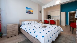 Een slaapkamer met een bed, nachtkastje en een bureau met stoelen.