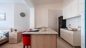 Een moderne keuken met een centraal eiland, witte kasten en een rode stoel.