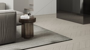 Een moderne woonkamer met een bank, een salontafel en een trap naar een hoger gelegen, donkerder gedeelte.