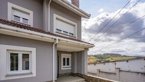 A two-story building with a balcony, a tiled roof, and a view of the countryside. - Vacation Home 'Santa Divina Relax Para 10 Personas' with Balcony and Wi-Fi (Asturias)