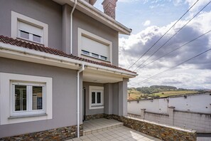 Ein zweistöckiges Gebäude mit Balkon, Ziegeldach und Blick auf die Landschaft.