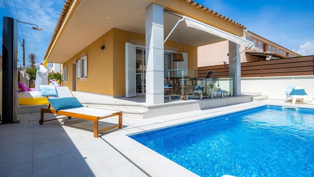 Ein Poolbereich mit Liege, einer verglasten Terrasse und einem klaren, blauen Pool.