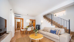 Ein modernes Wohnzimmer mit Sofa, Couchtisch, Fernseher und Treppe.