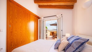 Ein Schlafzimmer mit einem großen Bett, einem Holzschrank und Blick auf eine Terrasse.