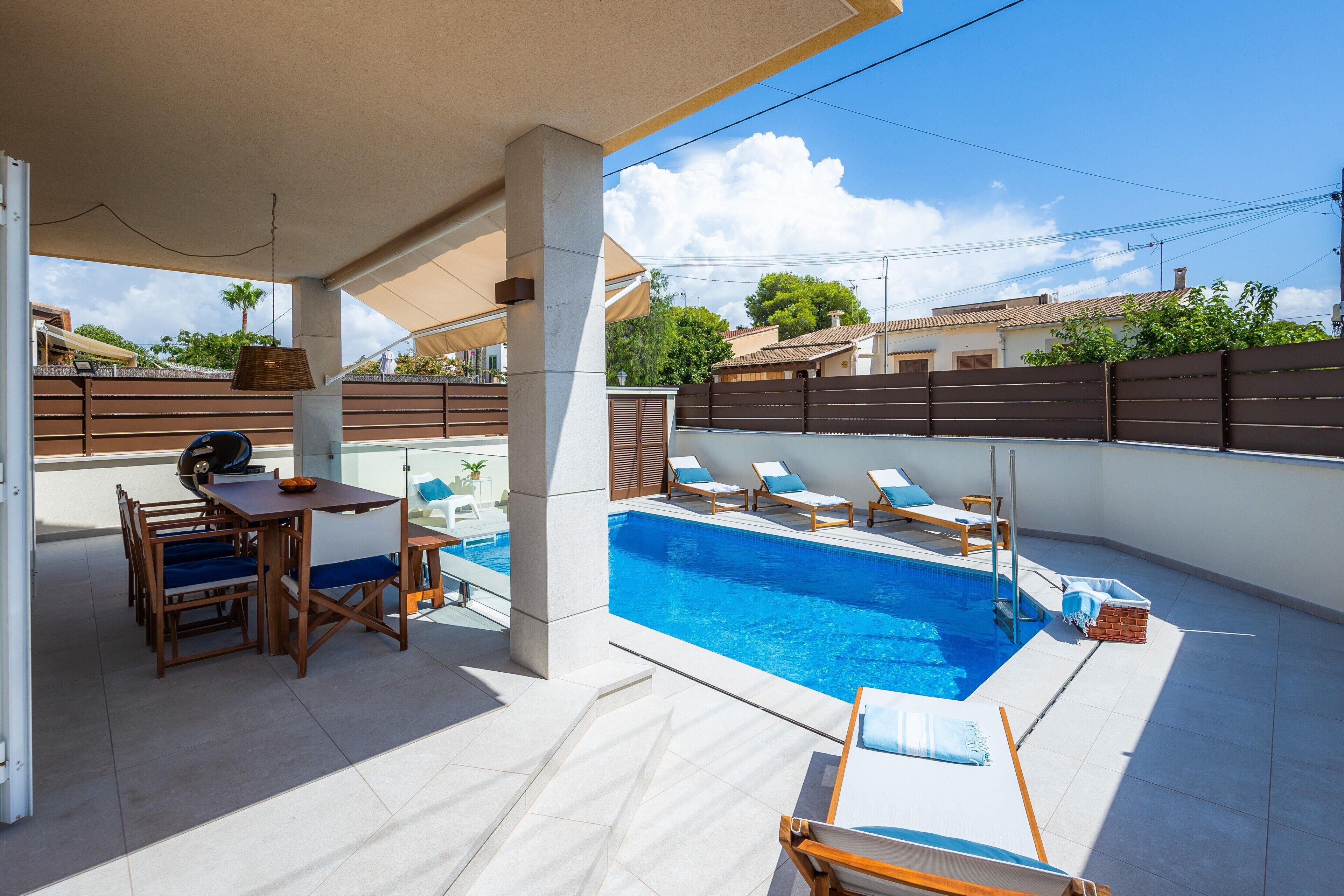 Un espace piscine aménagé sur le toit, avec une table et des chaises, une petite table avec un panier, et des chaises longues disposées autour de la piscine.