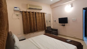 A hotel room with a bed, a ceiling fan, an air conditioning unit, a television, and a window. - Five stones By Earth Hotel Vadapalani (Chennai)