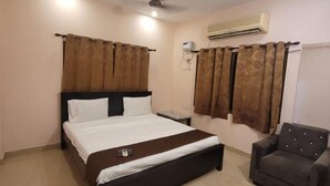 A bedroom with a bed, a chair, an air conditioning unit, and a ceiling fan. - Five stones By Earth Hotel Vadapalani (Chennai)