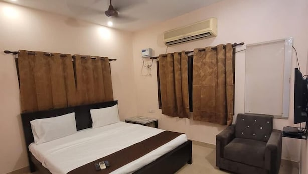 A bedroom with a bed, a chair, an air conditioning unit, and a ceiling fan. - Five stones By Earth Hotel Vadapalani (Chennai)