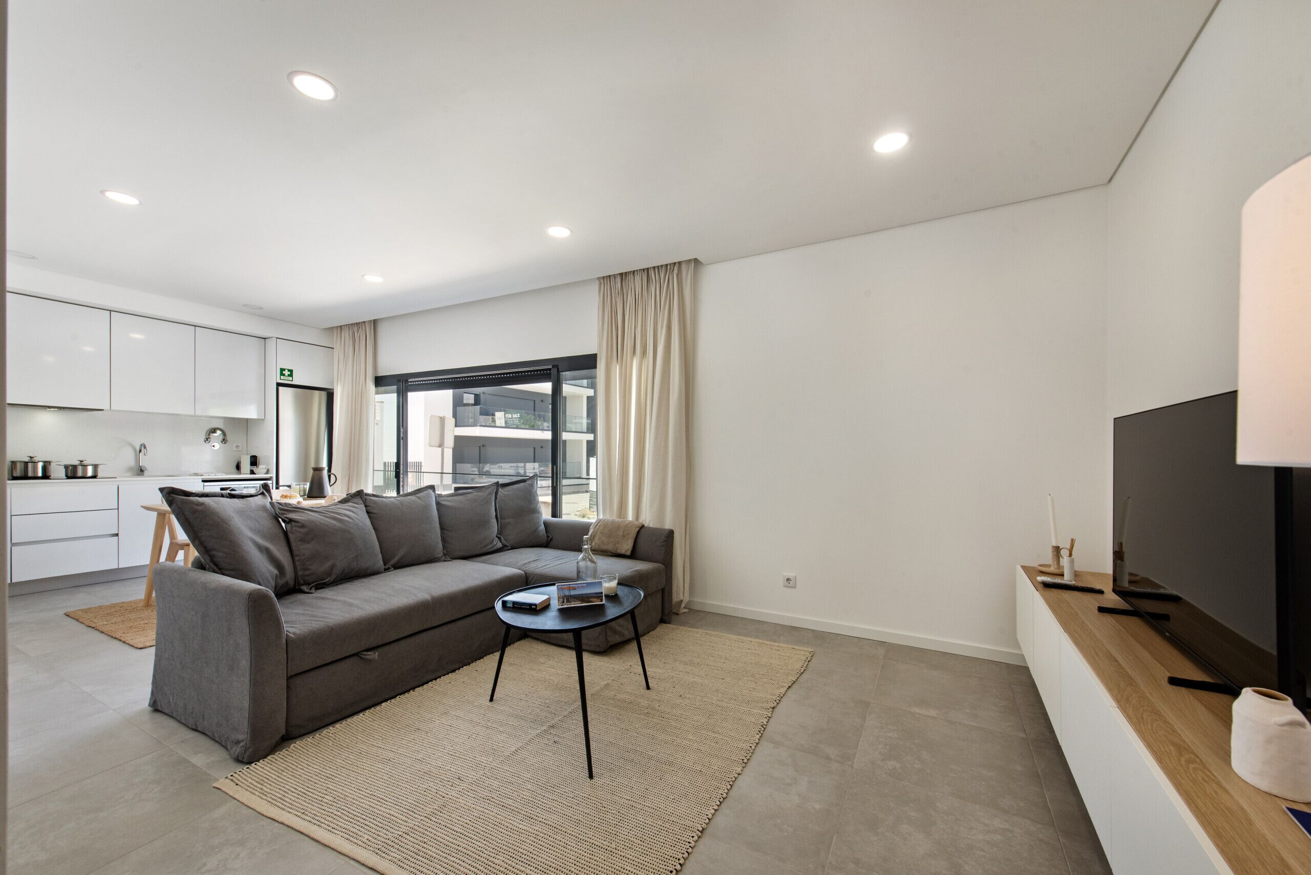 A modern living room with a grey sofa, a coffee table, and a TV on a wooden console.