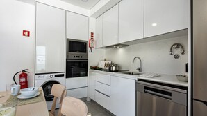 A modern kitchen with white cabinets, stainless steel appliances, a microwave, oven, dishwasher, and a sink.