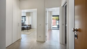A modern interior with a hallway leading to a living area and a balcony.