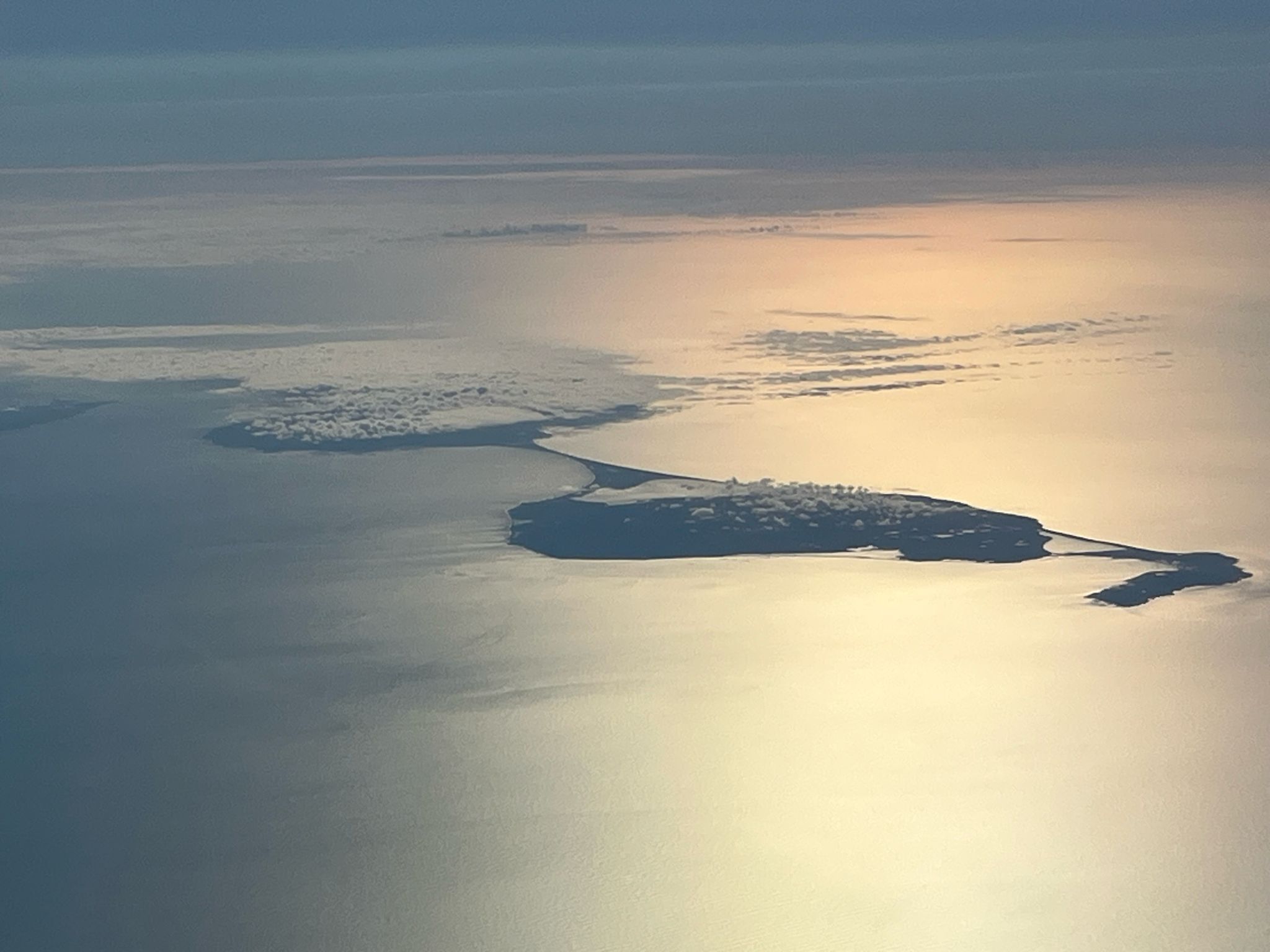 Luftaufnahme einer Küstenlandschaft mit einem großen Gewässer, einer kleinen Insel und einer Halbinsel.