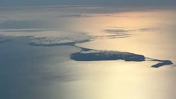 Luftaufnahme einer Küstenlandschaft mit einem großen Gewässer, einer kleinen Insel und einer Halbinsel.
