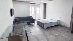 A modern room with a glass table, a sofa, and a bed.