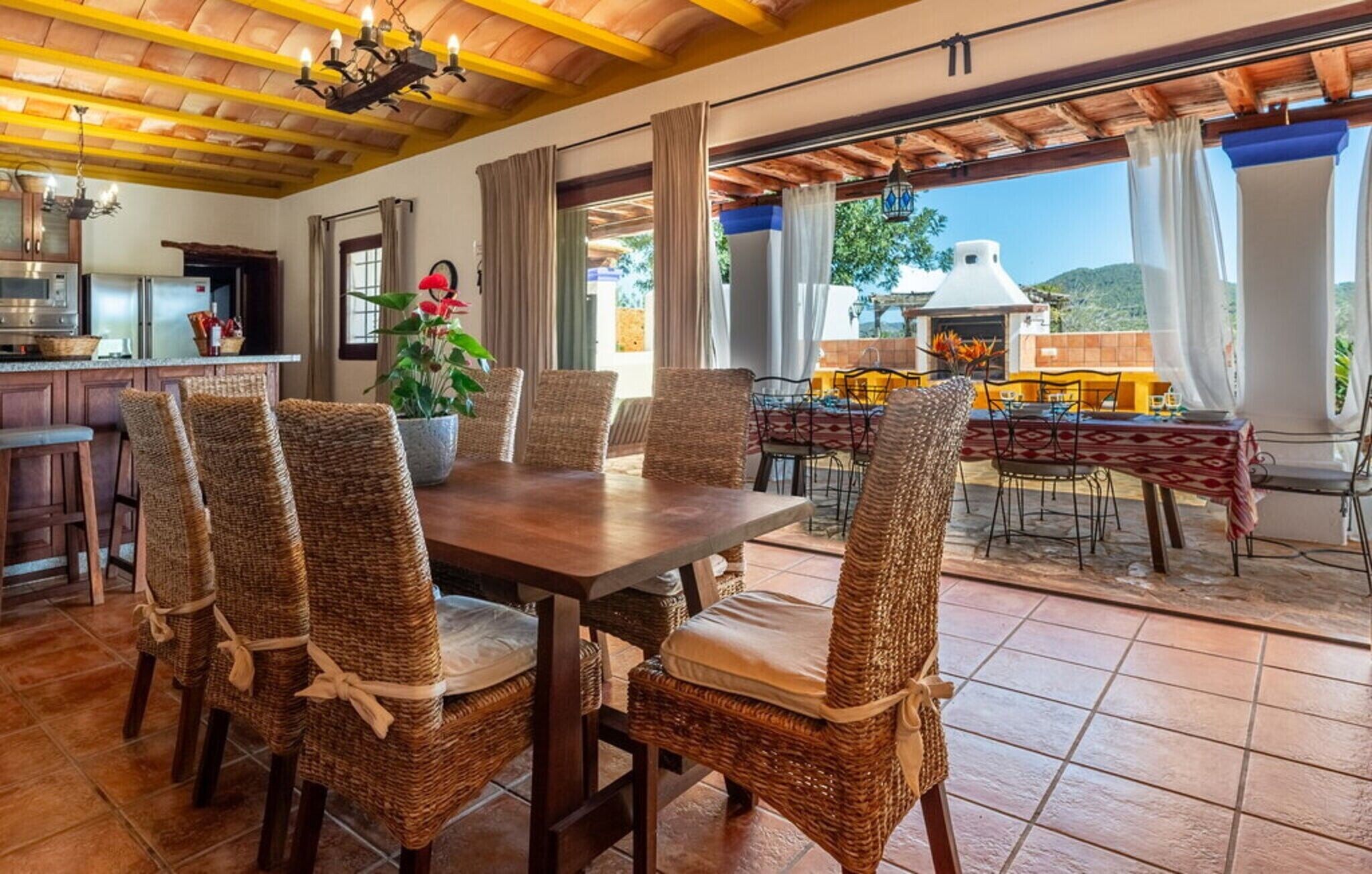 Un comedor con sillas de mimbre, una mesa de madera y vistas al exterior.