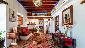 A traditional interior with a wooden ceiling, a sofa, a table, and a patterned rug.