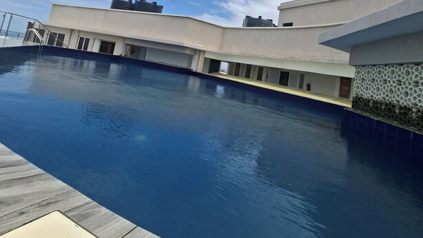 Una piscina con cubierta de madera y un edificio moderno al fondo.