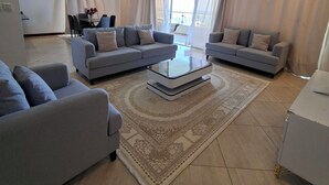 Una sala de estar amplia con dos sofás grises, una mesa de centro y un comedor con mesa y sillas.