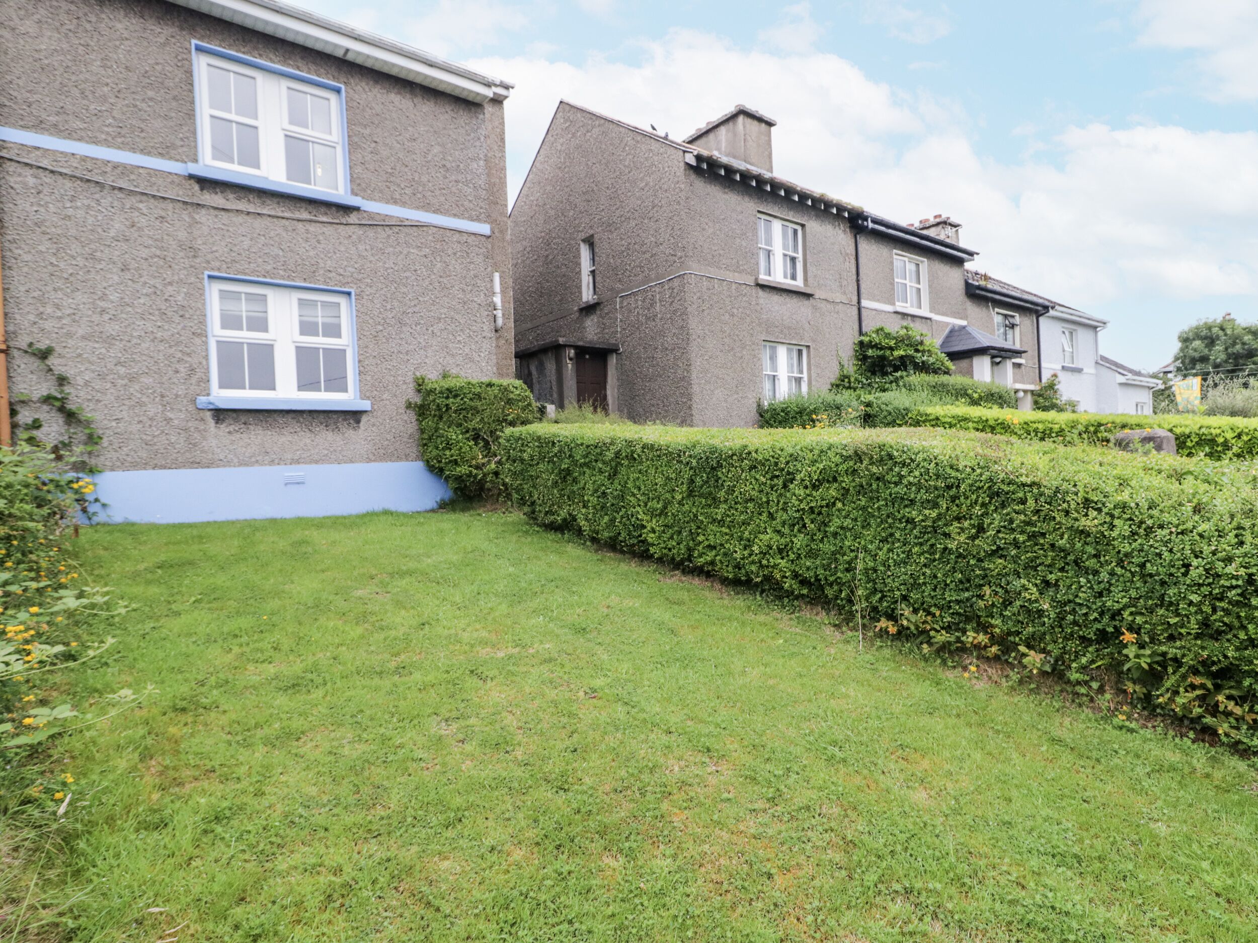 Een rij huizen met een verzorgd gazon en hagen.