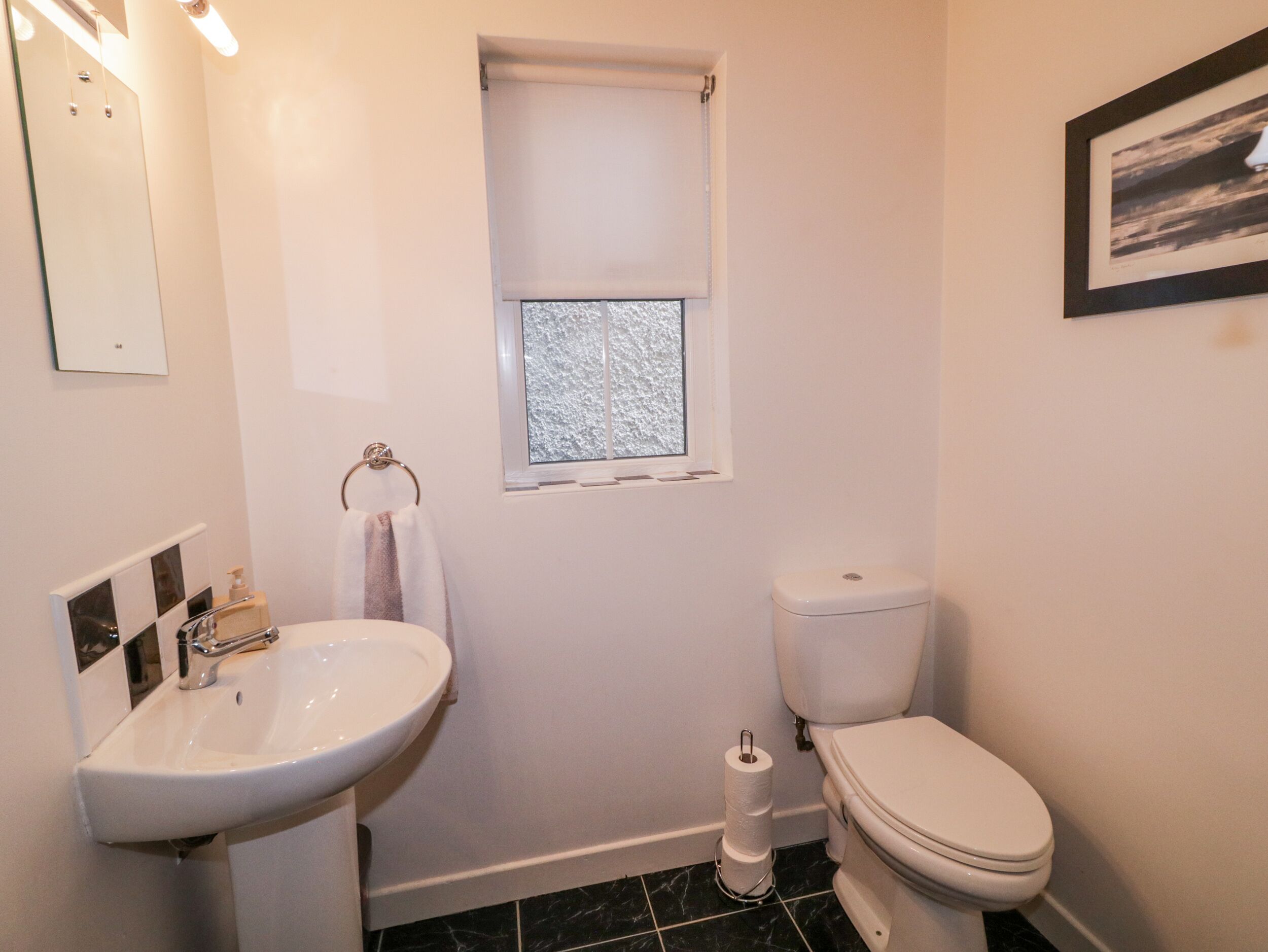 A bathroom with a white sink, toilet, and a window with a view of a snowy landscape.
