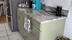 Een keuken met een koelkast, een koffiezetapparaat en een vaas met bloemen.