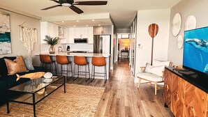 Una cocina moderna con armarios blancos, un refrigerador de acero inoxidable y una isla central con taburetes de bar.
