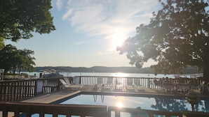 A pool area with lounge chairs and a wooden deck overlooking a body of water.