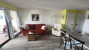 A living room with a red sofa, a beige armchair, a small table, and a wicker basket.