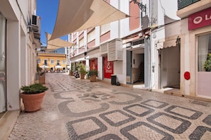 A narrow street with shops, a tiled pavement, and potted plants. - Faro Downtown Suites – Charming 1-Bedroom in the Heart of Faro (Faro)