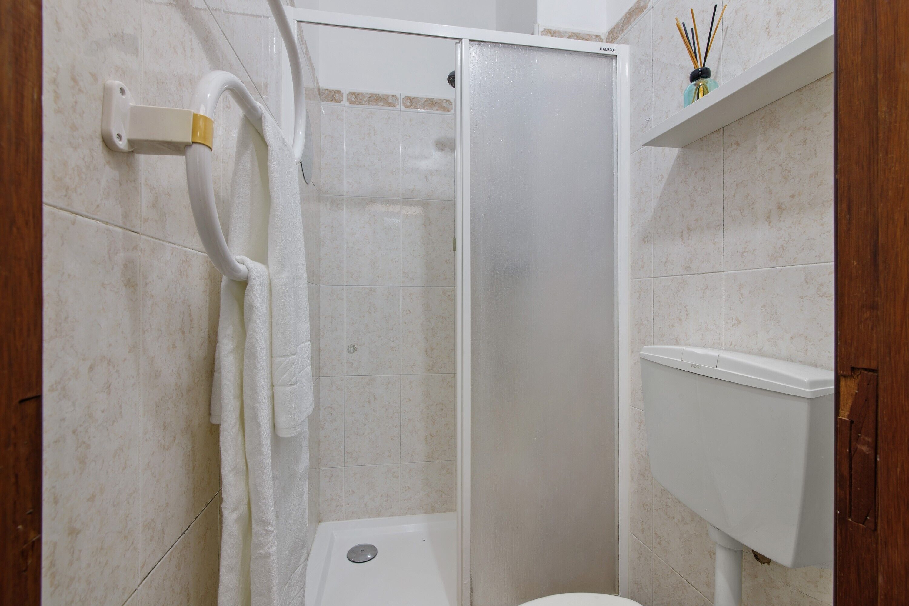 Ein Badezimmer mit Dusche, Toilette und Handtuchhalter.