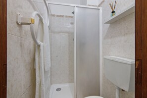 Un baño con ducha, inodoro y perchero para toallas.