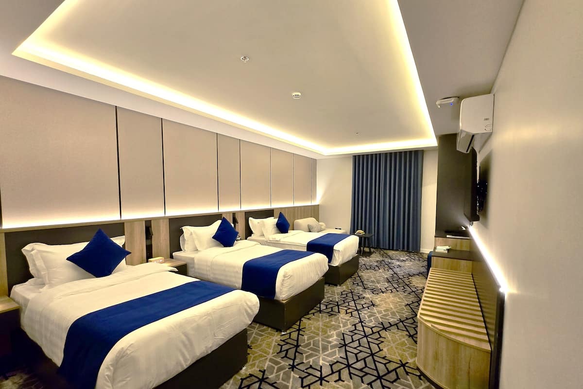 A hotel room with two beds, a TV, and a patterned carpet.