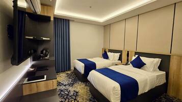 Habitación de hotel con dos camas, un escritorio, un espejo y una alfombra estampada.