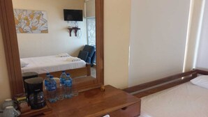 A hotel room with a wooden desk, a chair, a bed, a TV mounted on the wall, and a window with curtains. - Estudio con vista al oceano (Tola)