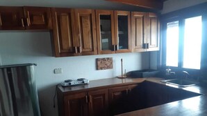 A kitchen with wooden cabinets, a stainless steel refrigerator, a gas stove, and a sink. - Apartamento con vista al mar (Tola)