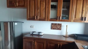 A kitchen with wooden cabinets, a stainless steel refrigerator, a gas stove, and a black countertop. - Apartamento con vista al mar (Tola)