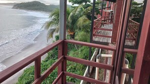 A wooden balcony with a view of the beach and ocean. - Apartamento con vista al mar (Tola)
