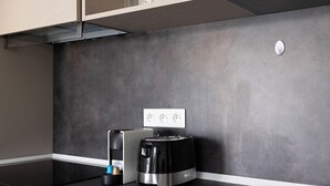 A modern kitchen with a black countertop, a Bosch coffee maker, and a built-in oven. - Le 202 Sainte Ségolène - 1 room, rénovated, heart of Metz (Metz)