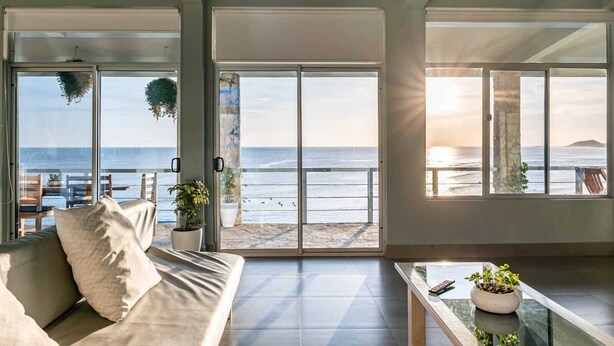 A spacious living area with large windows offering a view of the ocean. - Penthouse con vista al oceano (Tola)